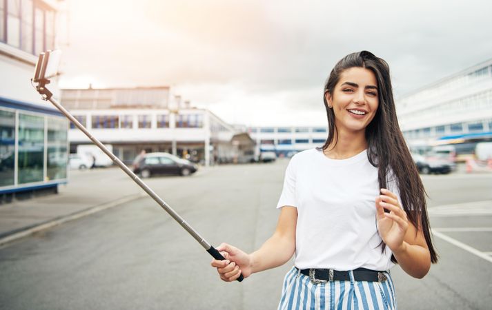 Tanned woman with selfie stick on overcast day
