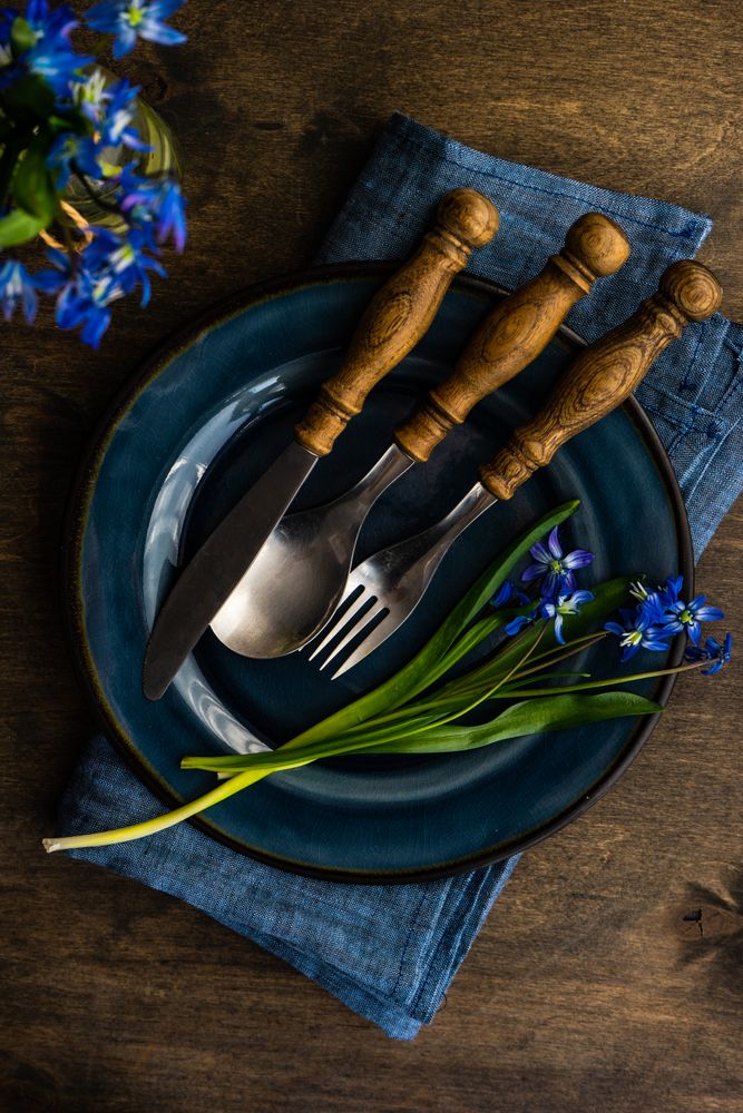 Spring table setting with blue scilla siberica on elegant navy plate