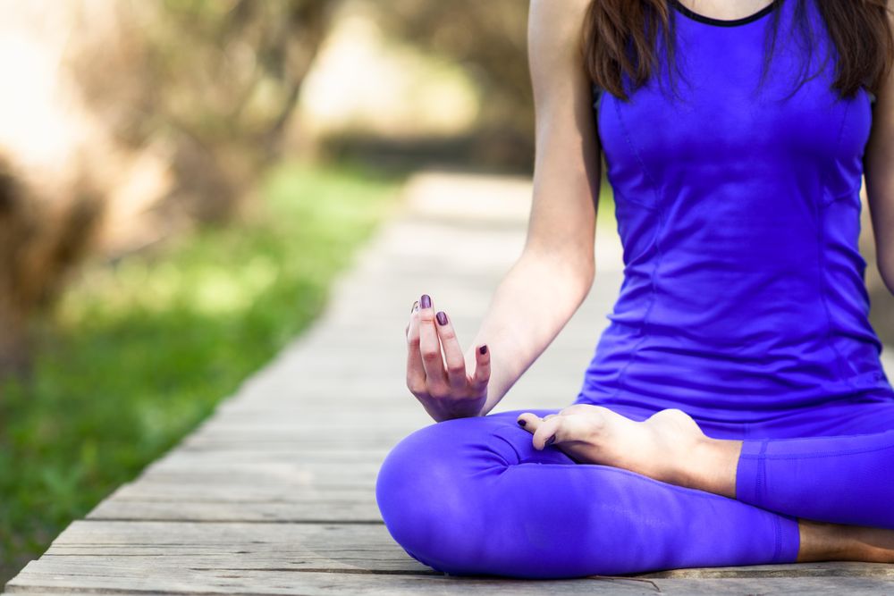 Female wearing purple sport clothes and sitting cross legged with space for text