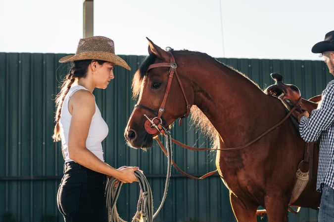Woman taking care of his brown horse in an equestrian center