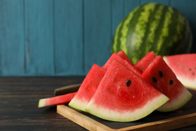 Composition with board with watermelon slices on wooden table
