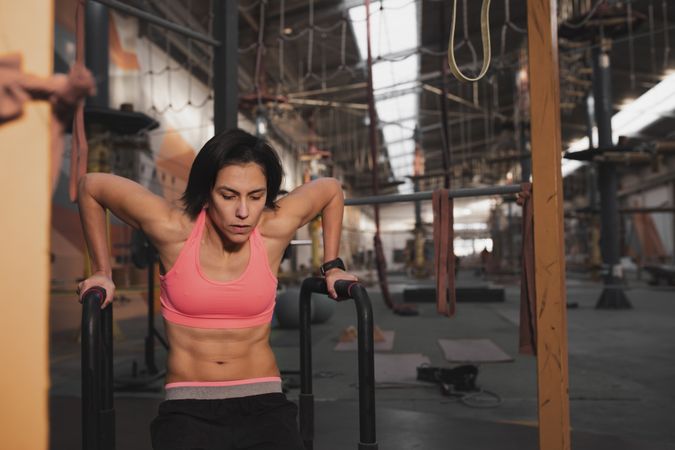Athletic woman training on parallel bars in gym