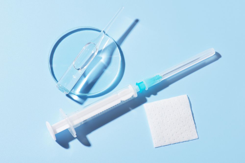 Needle and disinfectant pad on blue background