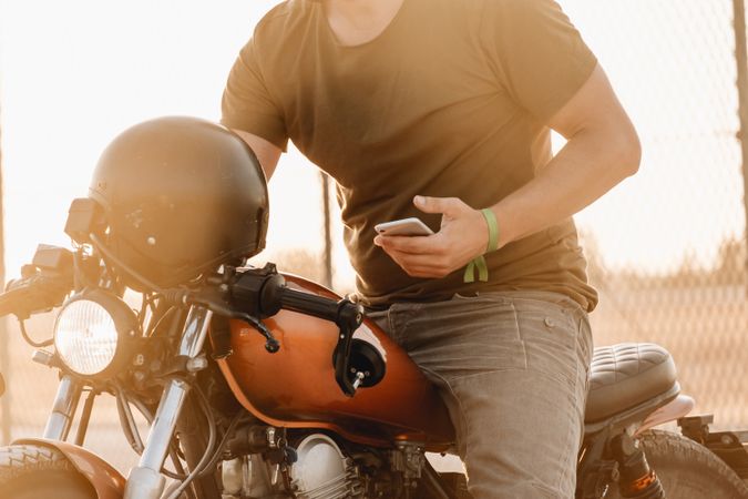 Man sitting on motorcycle and surfing mobile