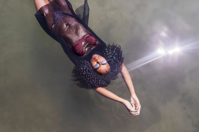 Beautiful young Black woman floating in a pool of water