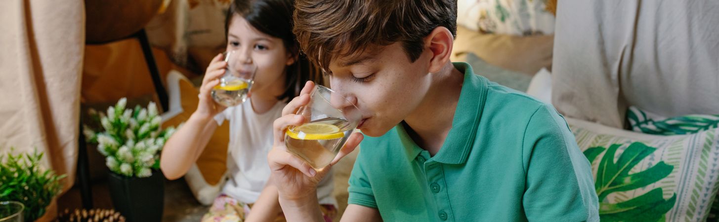 Boy drinking homemade lemonade with his sister