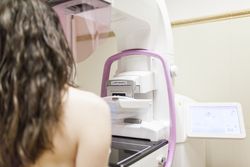 Female patient beside digital mammography unit