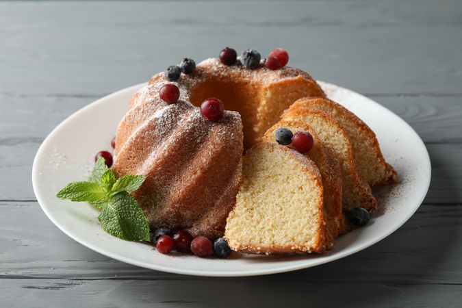 Cake with powdered sugar, berries and mint on wooden background, close up