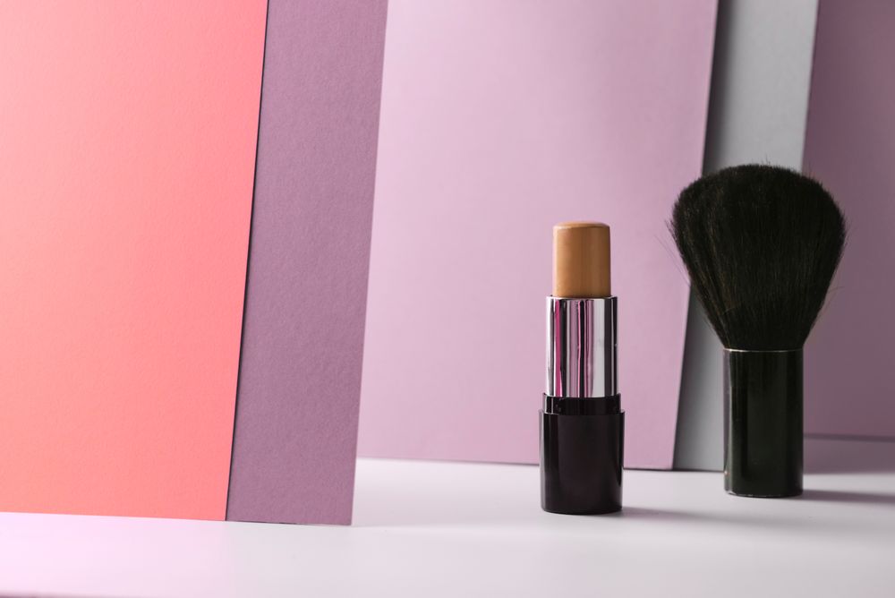 Concealer stick and make up brush on modern background