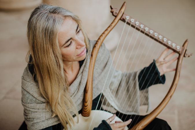 Romantic female musician playing lyre in terrace