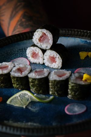 Anonymous waiter with delicious sushi rolls with salmon on tray
