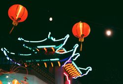 Red lit lanterns near pagoda under night sky