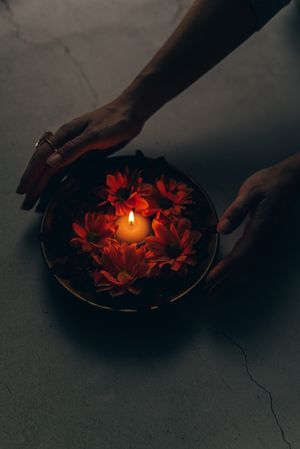 Hands holding a bowl of flowers and candles
