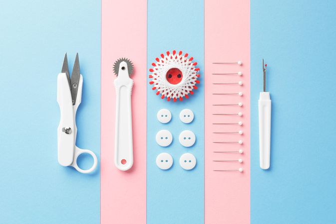 Sewing tools organized over pink and blue background