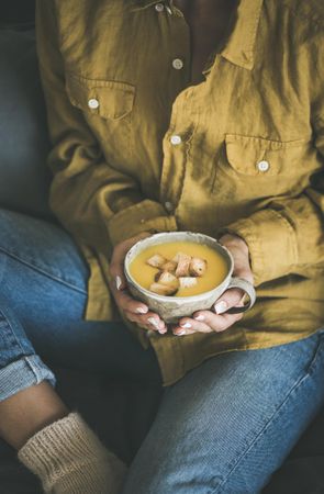 Woman in jeans holding cup of squash soup