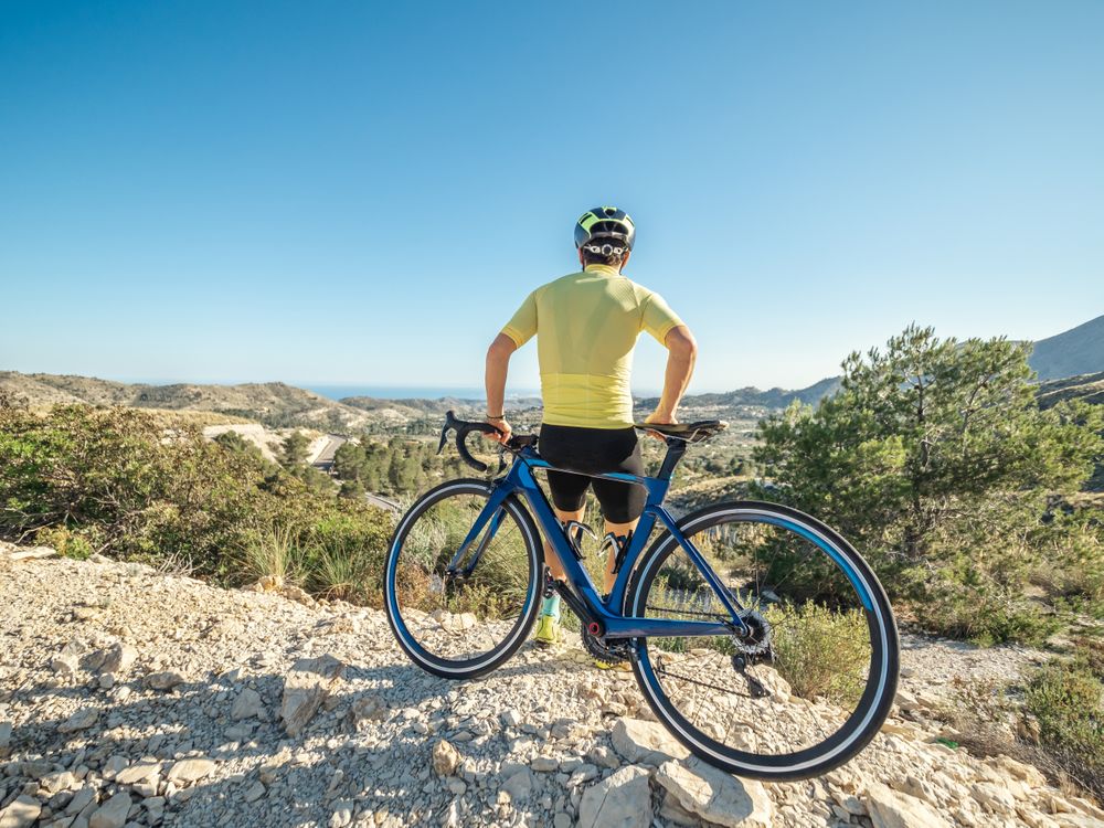 man resting and enjoying the views while riding a bicycle on a mountain road