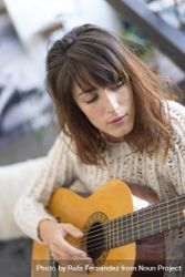 Female in wool sweater strumming acoustic guitar 42yR75