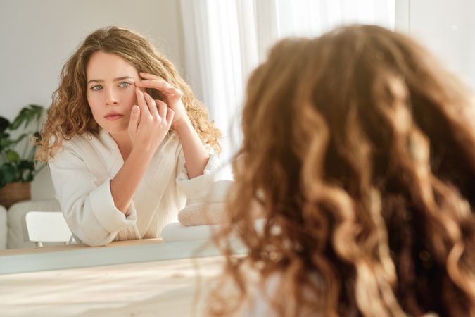 Woman looking at wrinkles in mirror