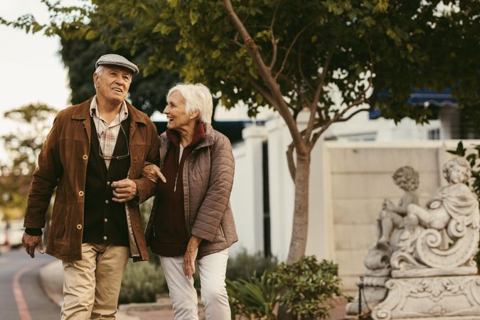 Portrait of happy older man and woman wearing warm clothing walking together outdoors