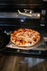 Pizza on a shovel fresh from the oven