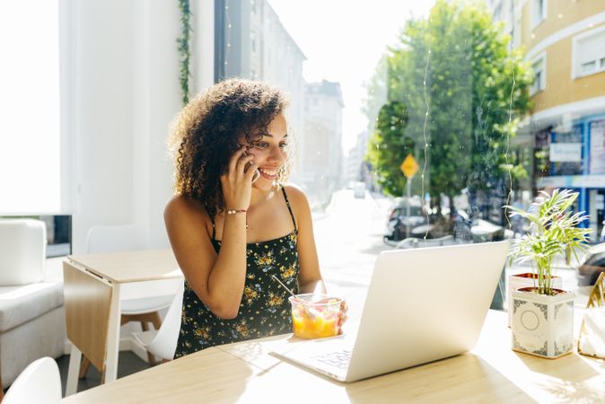 hispanic female with laptop enjoying healthy drink in cafe