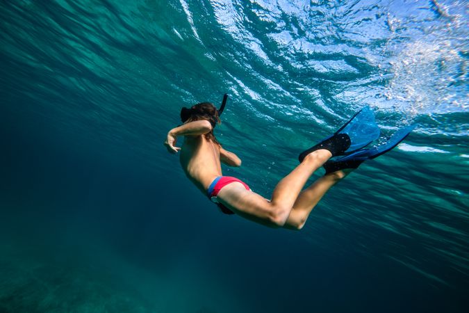 Teenager in diving mask and flippers swimming underwater in sea