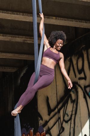 Fit woman doing yoga with aerial silks in city