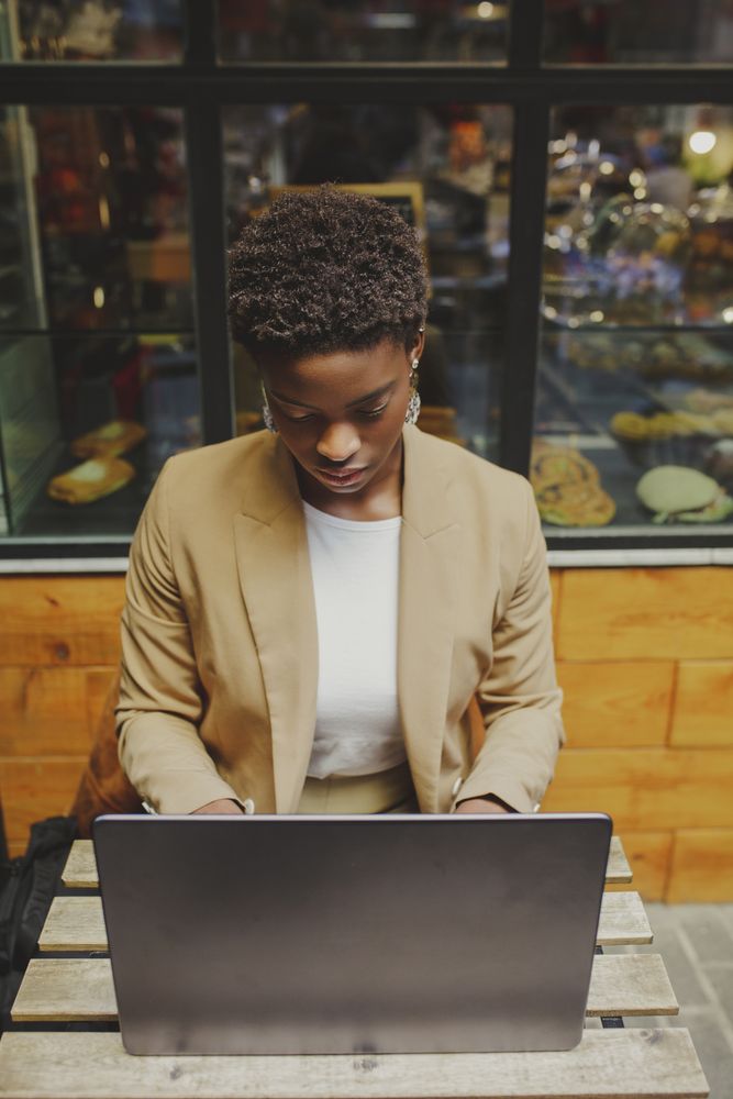 Smiling Black woman sitting at table with laptop in cafe
