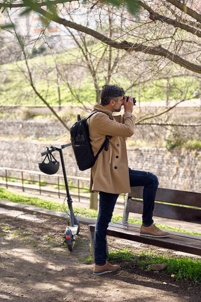 Male photographer stepping on bench and taking photo on camera