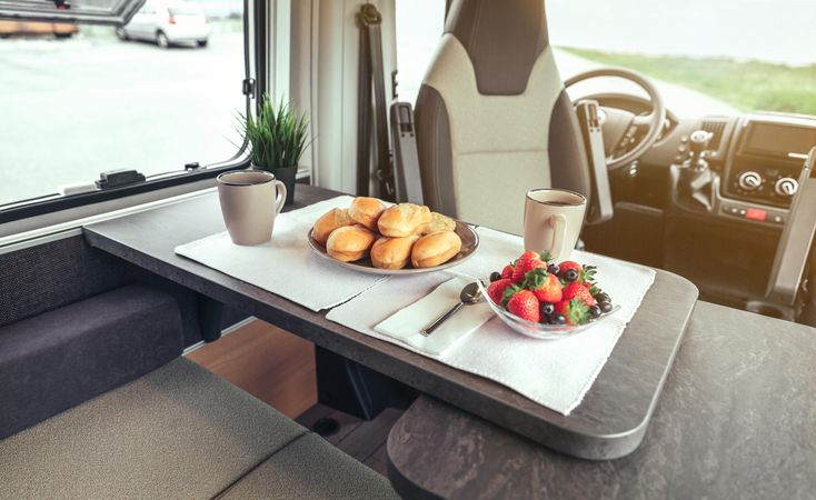 Breakfast pastries, coffee and bowl of berries in camper van