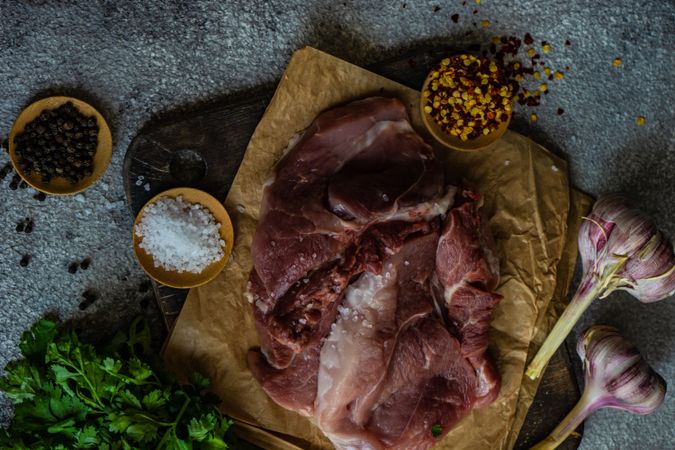 Cooking concept with meat, spices and herbs on stone table with copy space