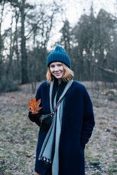 Woman surrounded by trees on cold day with red leaf