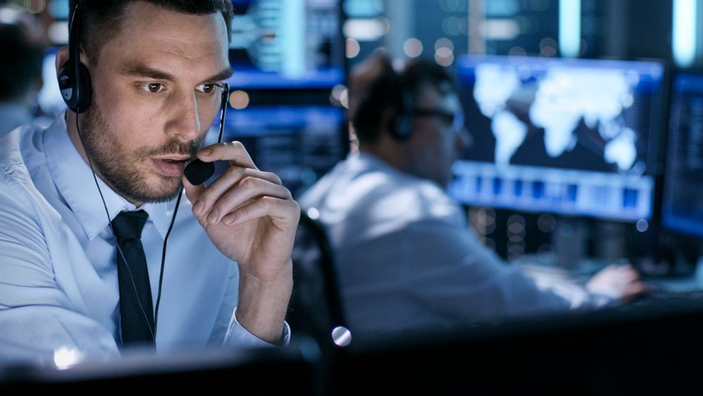 In Monitoring Room Technical Support Specialist Speaks into Headset.