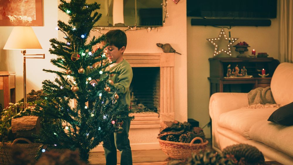 Boy decorating Christmas tree in evening