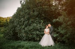 Smiling groom and bride hugging and kissing in park