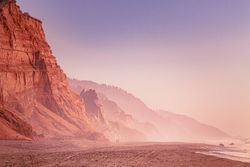Cliffs of Northern Californian beach with two people walking in the distance