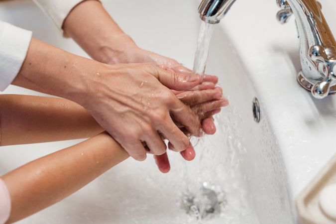 Cropped image of parent washing a child's hands on sink
