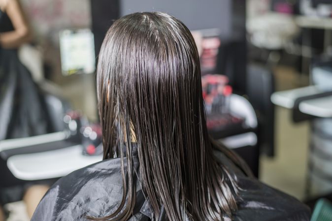Brunette woman with wet hair sitting in hair dresser’s