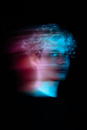 Blurry portrait of blonde young man with uv hair dye in a studio