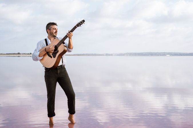 Inspired musician playing guitar at seaside