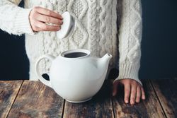 Woman opening top of big tea pot