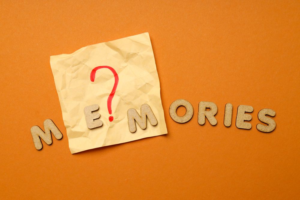 The word “Memories” written in cork on top of post it note on dusty orange background