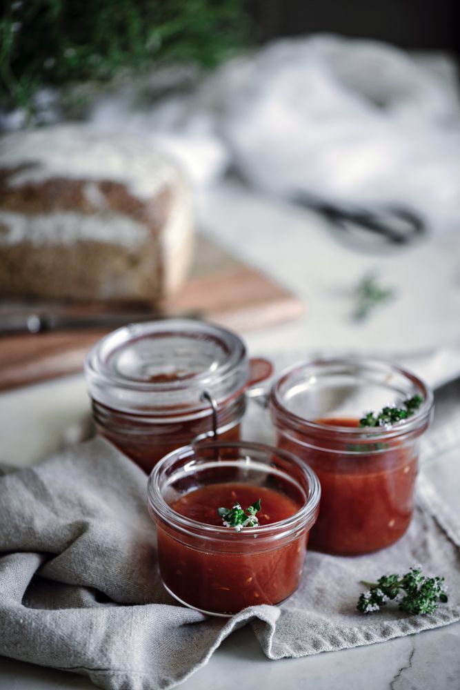 Fresh bread on napkin near tomatoes jam