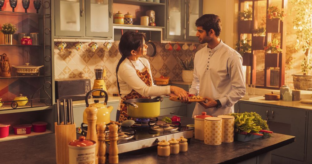 Playful Indian Couple Preparing Food in the Kitchen: Learning New Recipes