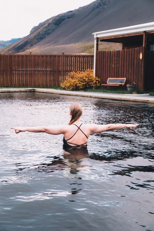 Woman in pool near sea and hills on shore