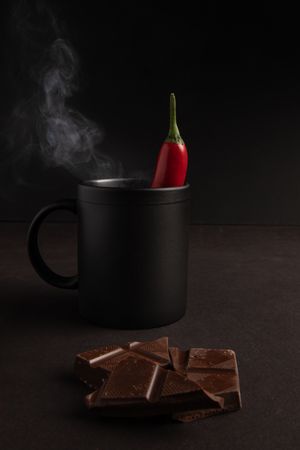 Chocolate near mug with hot drink and pepper