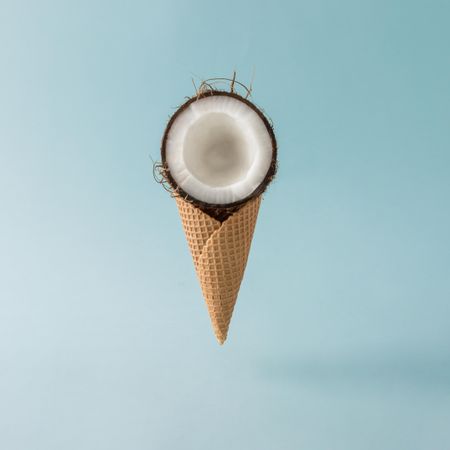 Coconut half in waffle cone on pastel blue background