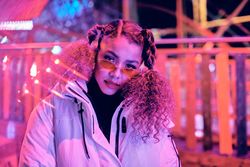 Young woman wearing red sunglasses beneath red light