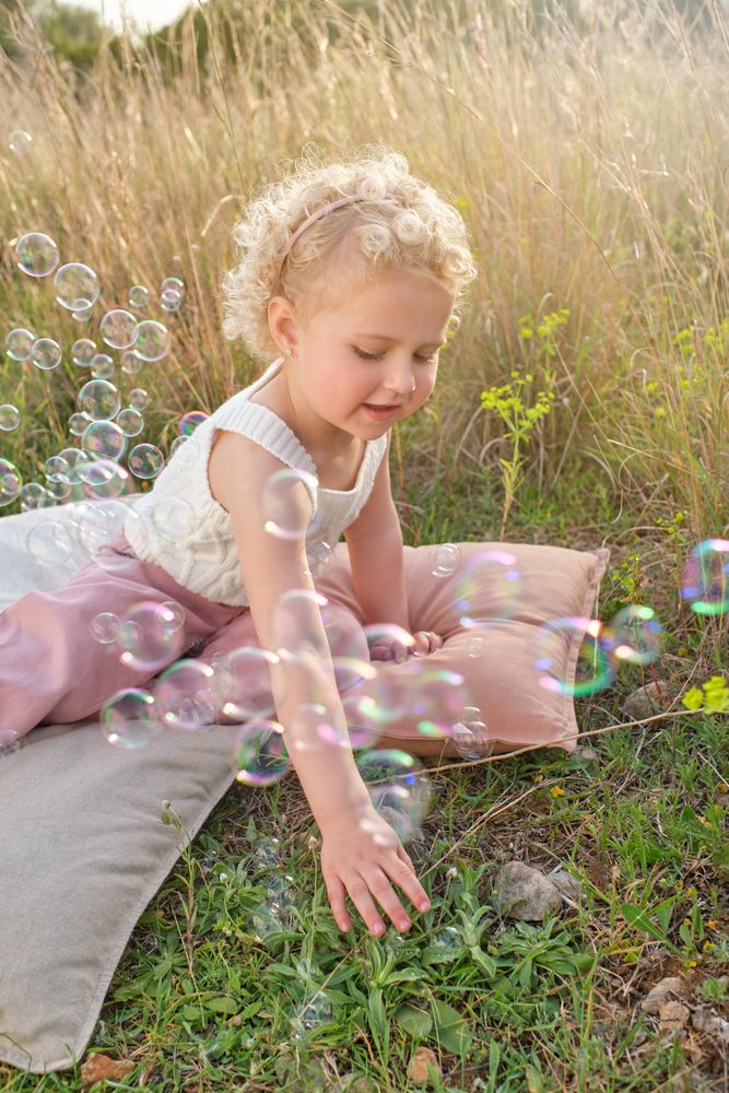 Happy girl playing with soap bubbles in sunny countryside