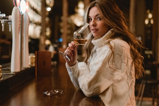 Stylish woman drinking wine in bar